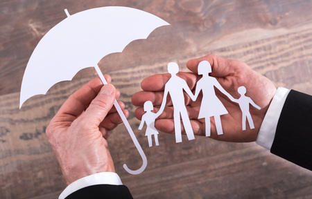 Hands holding a family and an umbrella - insurance conceptの写真素材