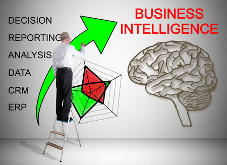 Man on a ladder drawing business intelligence concept on a wallの写真素材