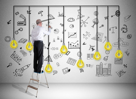Man on a ladder drawing creativity concept on a wallの写真素材