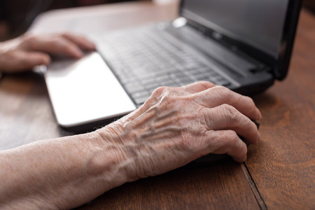 Old woman hand using the mouse of a computerの写真素材