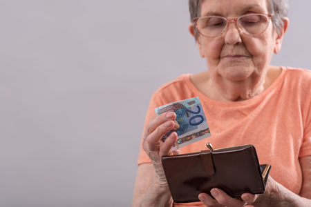 Old woman holding a banknote and her wallet