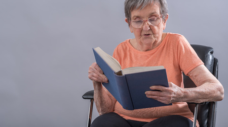 Old woman sitting reading a bookの写真素材