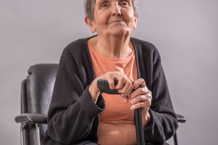 Senior woman sitting with her caneの写真素材