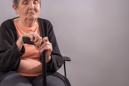 Unhappy senior woman sitting with her caneの写真素材