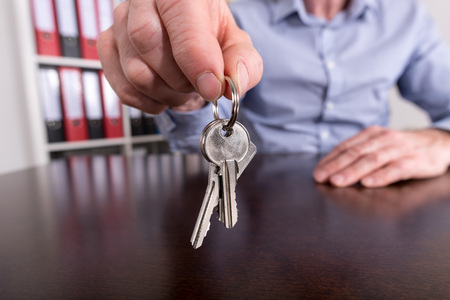 Estate agent offering house keys on a wooden table