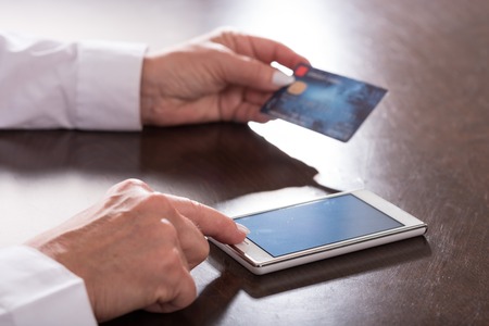 Woman hands using smartphone and credit card for online paymentの写真素材
