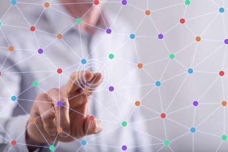 Man touching a virtual network on a touch screen with his fingerの写真素材