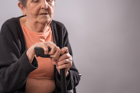 Old woman sitting and holding her caneの写真素材