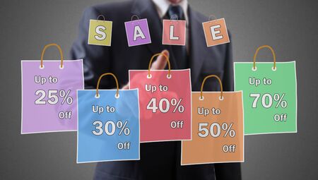 Sale concept shown by a businessman in backgroundの写真素材