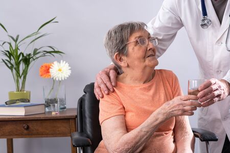 Doctor giving a glass of water to an elderly patientの写真素材
