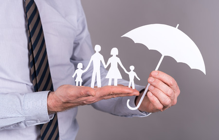 Man holding an umbrella protecting a familyの写真素材