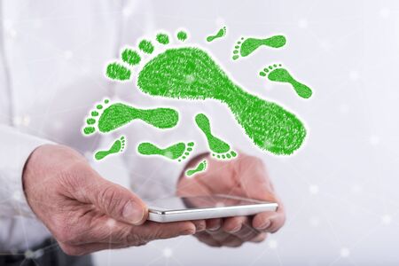Carbon footprint concept above a smartphone held by handsの写真素材