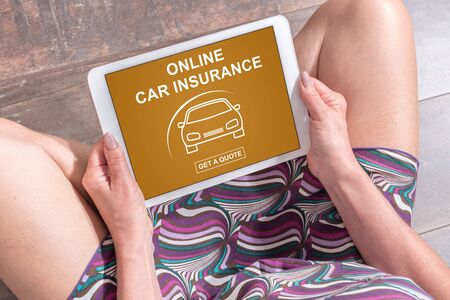 Woman sitting on the floor with a tablet showing online car insurance conceptの写真素材
