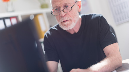 Senior man working on a laptop in officeの写真素材