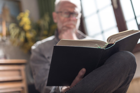 Senior man reading a book at home, hard light effect