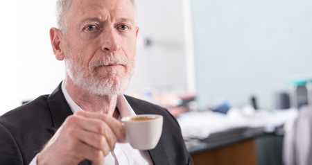 Portrait of senior businessman holding a cup of coffeeの写真素材