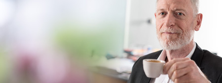 Portrait of satisfied senior businessman holding a cup of coffeeの写真素材