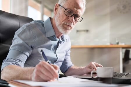 Senior businessman taking notes in office, hard light, light effect