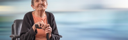 Old woman sitting and holding her caneの写真素材