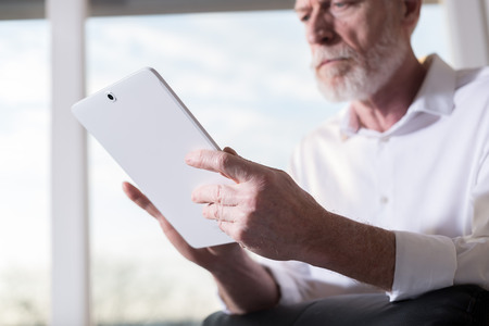 Senior businessman using a digital tablet in office, hard light