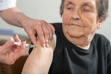 Nurse giving an injection to senior womanの写真素材