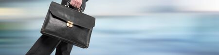 Businessman walking with his briefcase on blurred backgroundの写真素材