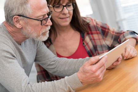 Modern mature couple using tablet at homeの写真素材