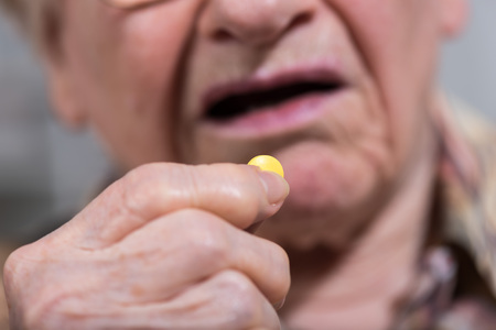 Old woman taking medication at homeの写真素材