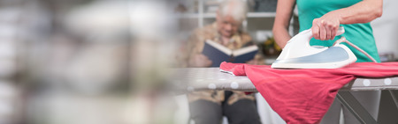Home helper ironing clothes for elderly womanの写真素材