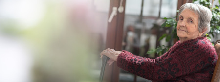 Old woman sitting with her hands on a caneの写真素材