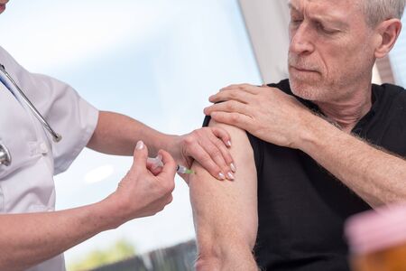 Female doctor vaccinating a senior manの写真素材