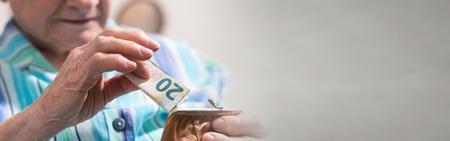 Old woman taking out a banknote from her walletの写真素材