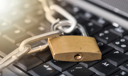 Computer security concept with a padlock and a chain on a keyboard, light effect