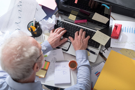Businessman working on a cluttered and messy desk, top viewの写真素材