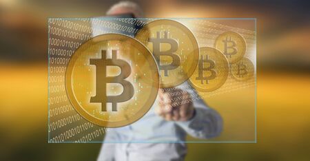Man wearing a reality virtual headset touching a bitcoin currency concept on a touch screen with his fingerの写真素材