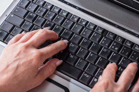 Female hands typing on a laptop keyboardの写真素材