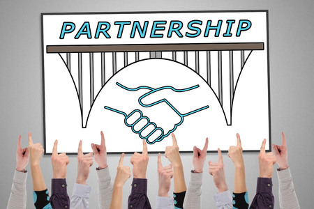 Partnership concept on a whiteboard pointed by several fingersの写真素材