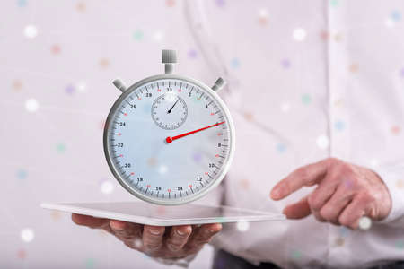 Time concept above a tablet held by a man in backgroundの写真素材