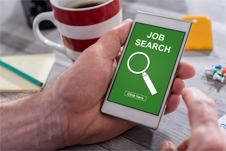 Male hand holding a smartphone with job search conceptの写真素材