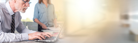 Mature businessman using a laptop in office, light effect