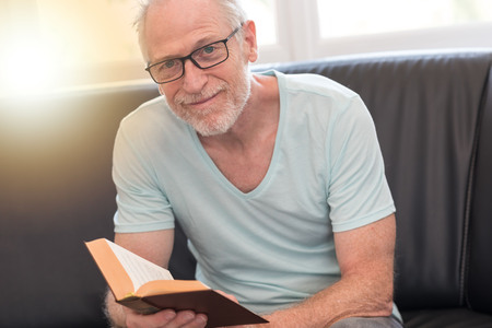 Portrait of mature man reading a book at home, light effectの写真素材