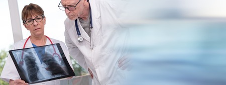 Two doctors examining x-ray report in medical officeの写真素材