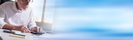 Senior businessman using a calculator in officeの写真素材