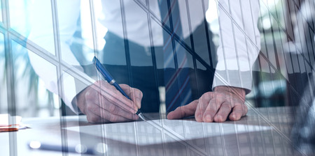 Businessman signing a document in office, double exposure, light effectの写真素材