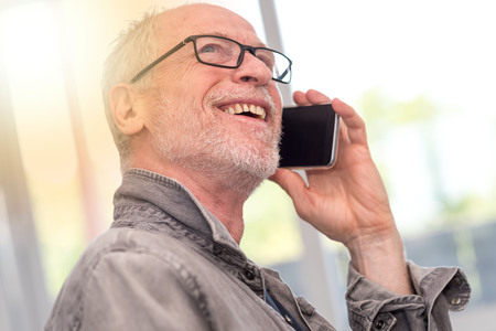 Portrait of smiling mature man talking on mobil phone, light effectの写真素材