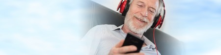 Modern mature man listening music on mobile phone at homeの写真素材