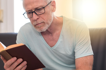 Portrait of mature man reading a book at home, light effectの写真素材