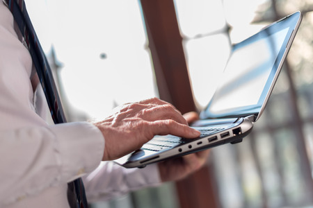 Businessman standing, working on laptopの写真素材