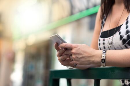 Young woman using her mobile phone in the street, light effect