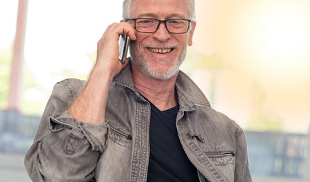 Portrait of smiling mature man talking on mobil phone, light effectの写真素材